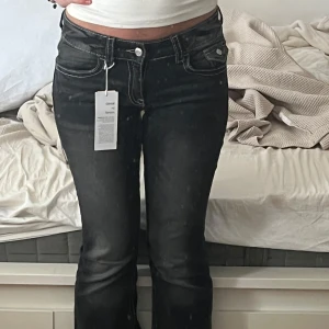 Gråa/svarta bootcut jeans Gina tricot  - Helt nya lågmidjade gråa/svarta jeans med vit stichdelatjer!💕Endast testade!👖 Köpta för 345kr💸 Storlek 164 - alltså xs/s -34/36