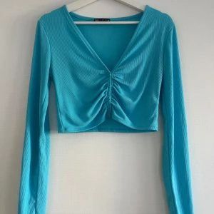 Turkos croppad topp från Zara - Säljer en snygg turkos croppad topp från Zara med långa ärmar och en v-ringad design. Perfekt för fest eller bara pigga upp vardagen! Använd ett fåtal gånger! 