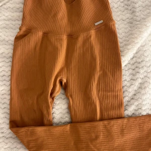 Orange  ribbade leggings från Aim'n - Säljer ett par snygga Orange leggings från Aim'n. De är ribbade och har en hög midja för extra komfort. Perfekta för både träning och avslappning. Materialet är en blandning av polyamid och elastan vilket ger en skön stretch. 