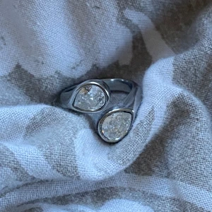 Rostfri silver ring med två droppformade stenar - Elegant silverring med två droppformade klara stenar. Perfekt för att ge en stilren och modern touch till din look. JUSTERBAR