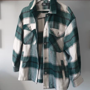 Rutig grön skjortjacka från Zara - Säljer en snygg rutig overshirt från Zara i grönt och vitt. Jackan har långa ärmar och knappar framtill samt två bröstfickor med lock. Ullblandning så känns som att ha på sig en mysig filt! Storlek XS men skulle säga att den passar XXS-M beroende på passform 💚 Nypris: ca 699kr 🌟 Pris kan diskuteras 