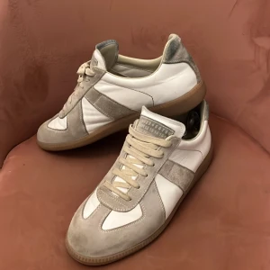Vit/grå maison margiela  - Vita maison Margielas. Använda med en mindre defekt på höger sko, sunna på bild 4. Annars är de nästintill perfekta. Pris går självklart att diskuteras!