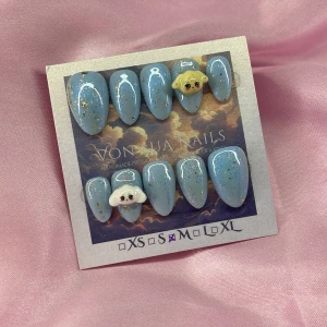 BlueAniteez(M);Short Almond - Handgjorda press-on naglar i kort mandelform med skimrande blå bas, guldglitter och vita detaljer. Två naglar har söta 3D-djurmotiv (Aniteez) i beige och vitt. Perfekt för dig som vill ha unika och kreativa naglar med extra wow-faktor.