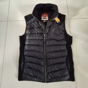 Väst från Parajumpers - Säljer en snygg svart dunväst från Parajumpers👌 Västen har dragkedja framtill, bröstficka med dragkedja och en gul knäppare vid halsen. Perfekt för lager-på-lager och håller dig varm under kyliga dagar. Jag har knappt använt västen så den är näst till sprillans ny👍 Den är givetvis äkta! Hör av er vid funderingar😁