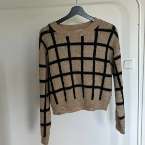 Beige rutig stickad tröja från NA-KD - Säljer en beige stickad tröja från NA-KD med svart rutigt mönster. Tröjan har rund halsringning, ribbade muddar och lång ärm. Använt mycket vilket resulterat i att den är nopprig men jag tar bort det så gått det går innan den skickas!💞