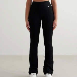 Svarta ribbade bootcut byxor Aimn  - Säljer ett par svarta ribbade byxor med bootcut-silhuett och hög midja. Byxorna är stretchiga och sitter tajt upptill med utsvängda ben. Perfekta för en chill och trendig look.