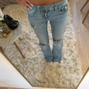Ljusblå straight jeans från Gina Tricot - Säljer ett par ljusblå jeans från Gina Tricot med hål och slitningar jag gjort själv!! low waist🥰