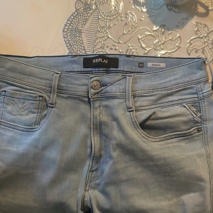 Replay Anbass ljusblå jeans herr - Säljer ett par snygga ljusblå Replay Anbass jeans i klassisk femficksmodell. Jeansen har normal passform, raka ben och är tillverkade i mjukt denimtyg. Perfekta för dig som gillar stilrena och bekväma jeans med diskreta detaljer.