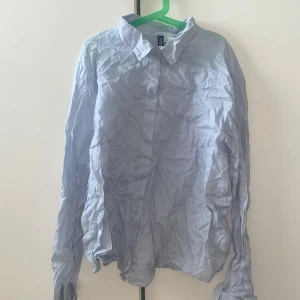 Ljusblå skjorta från H&M Divided L - Ljusblå skjorta från H&M Divided i storlek L. Klassisk modell med krage, knäppning framtill och långa ärmar. Skjortan är tillverkad i bomull och har en enkel, stilren look som passar till många olika outfits. Den köper skjortan kommer få den så klart strykt och inte som i bilden
