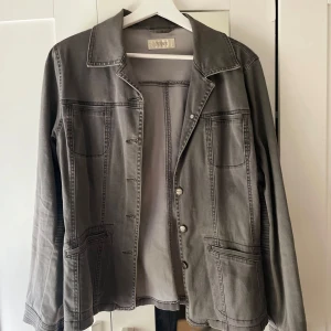 Grå jeansjacka från Intown - Snygg grå jeansjacka från Intown med klassisk krage, framfickor och knappar. Jackan har raka linjer och synliga sömmar som ger en cool vibe. Perfekt att slänga över en hoodie eller t-shirt för en chill look.