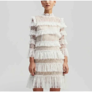 Vit spetsklänning från by malina, storlek XS - Supersöt vit kort spetsklänning med flera lager volanger och hög krage. Nypris 2800kr. Aldrig använt, prislappen är kvar. Skriv om fler frågor eller bilder.