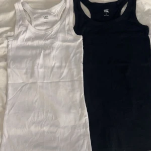 2-pack linnen från lager 157, svart & vit - Två klassiska linnen från 157 i svart och vitt. Båda har rundad halsringning och ärmlös design, perfekta att styla till jeans eller shorts. Säljes som ett set i storlek S.