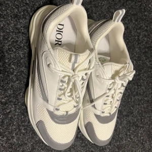 B22 - Snygga chunky sneakers i vitt och grått med mesh och skinnpaneler. Skorna har en kraftig sula, rund tå och coola detaljer som perforeringar och snörning. Perfekta för dig som vill sticka ut med exklusiva och trendiga sneakers.