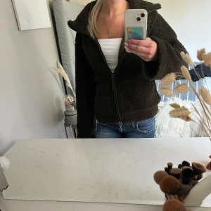 Mörkgrön teddyjacka med dragkedja - Supermysig teddyjacka med hög krage och hel dragkedja framtill. Jackan har två stora fickor och är i fluffigt teddy-material som håller dig varm. Perfekt för kyliga dagar och ger en chill vibe till din outfit. Inte använd alls mycket 