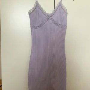 Ljuslila ribbad kortklänning med spets - Supersöt ljuslila kortklänning med tunna axelband, ribbat tyg och spetsdetaljer vid urringningen. 