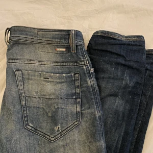 Blå slitna jeans från Diesel - Riktigt snygga blå jeans från Diesel med distressed look, hål och slitningar framtill. Klassisk femficksmodell med ljus tvätt och coola detaljer. Jeansen har normal passform och är tillverkade i robust denim. Perfekta för dig som gillar en edgy streetstil.