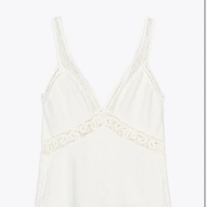 Vit spetsklänning med v-ringning - Supersöt vit klänning med v-ringad hals och breda axelband. Klänningen har fina spetsdetaljer längs halsringningen och midjan, samt ett romantiskt mönster framtill. Perfekt för sommarens alla tillfällen och ger en fräsch och bohemisk vibe🌵☀️