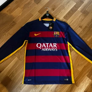 FC Barcelona Neymar 11 långärmad tröja - Säljer FC Barcelona långärmad matchtröja från Nike med Neymar och nummer 11 på ryggen. Tröjan har breda marinblå och röda ränder, gula detaljer vid krage och sidor, samt klubbmärke och Qatar Airways-tryck på bröstet. Tillverkad i lätt polyester med Dri-FIT.