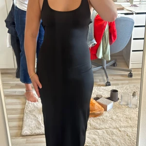 Klänning med öppen rygg - Supersnygg svart långklänning med smala axelband som korsas i ryggen och knyts. Passar XS-S. Helt oanvänd