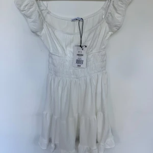 Vit kortklänning från Bershka - Supersöt oanvänd vit kortklänning från Bershka med inbyggda shorts!  Säljer även denna i storlek S