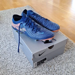 Nike Phantom GX II Elite "Haaland" FG fotbollsskor  - Säljer dessa Nike Phantom GX II Elite "Haaland" FG fotbollsskor i storlek 45. Köpt i maj och använda fåtal gånger då dem inte användes under sommaren. Skicket är jättebra och det finns inga slitningar och defekter på skon. Köpt från Unisport affären i Stockholm. Dustbag och originellbox ingår. Skick: 9/10