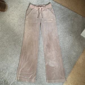 Beiga mjukisbyxor Juicy Couture XXS - Supermjuka beiga mjukisbyxor från Juicy Couture , de storlek xxs men mer som XS-S. med bred resår och snörning i midjan. Byxorna har raka ben, stora fickor fram och bakfickor med knapp. Ny pris 1400 från juicy couture.