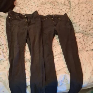 Svarta jeansbyxor från 157, stl L - Två par svarta jeansbyxor från 157 i storlek L. Klassisk femficksmodell med raka ben och knappgylf. Jeansen har en enkel design utan synliga mönster eller detaljer, perfekta för en clean och stilren look. Materialet är slitstarkt denim som håller formen.