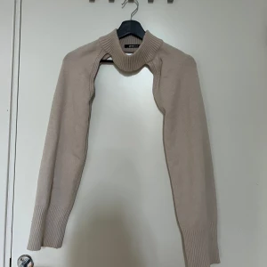 Beige stickad bolero från Gina Tricot - Trendig beige stickad bolero från Gina Tricot med polokrage och långa ärmar.