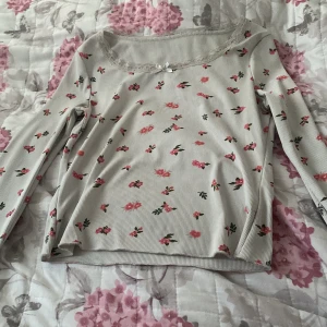 Blommig långärmad topp med spets - Supersöt långärmad topp med blommor. Hsr synligt slitage men inget man lägger märke till om man inte vet om det 