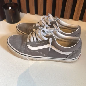Gråa Vans Old Skool sneakers - Klassiska Vans Old Skool sneakers i grått med vit sula och vit sidostrip. Skorna har snörning, rund tå och är tillverkade i canvas och mocka. Perfekta för en avslappnad streetstyle-look. Box tillkommer och tvättar dem innan jag skickar 