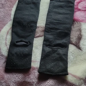 Svarta långa strumpor med hål - Svarta, långa strumpor i ett mjukt och stretchigt material. De har ett hål på vardera strumpa, perfekt för dig som vill ha en edgy och unik look. Passar bra till sneakers eller boots och ger en cool vibe till outfiten.