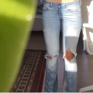 Ljusblå lågmidjade håliga slitna bootcut jeans - Midjemått 37 MEN stretchar ut några cm till. Innerbenslängden ca 79 cm! Säljer ett par lågmidjade ljusblå jeans med bootcut passform och slitna detaljer vid knäna. Tillsydd kile vid vaderna som ger en bootcut design🩷Stretchiga!