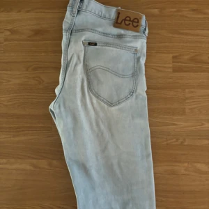 Lee jeans Daren Zip Fly - Säljer ett par ljusblå jeans från Lee, modell Daren Zip Fly. Klassisk femficksdesign med dragkedjegylf och Lee-lapp bak i midjan. Jeansen har en rak passform och är perfekta för en avslappnad stil.