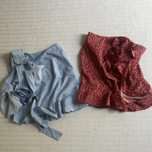 Två omlottkjolar med volangkant - Säljer två omlottkjolar, en i ljusblått och en i vinrött, båda med småblommigt mönster och volangdetaljer längs kanten. Kjolarna knyts i midjan och har en feminin, flowy känsla. Perfekta för vår och sommar! båda ingår💞💞