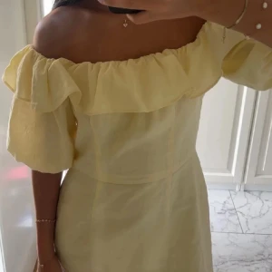 Gul offshoulder klänning med volang - Söt gul klänning med offshoulder-modell och volangdetalj upptill. Storlek xs, fint skick.