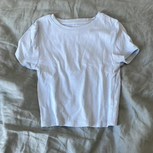 Ljusblå ribbad t-shirt från FSBN Sister - Säljer en ljusblå ribbad t-shirt från FSBN Sister i storlek XS. T-shirten har korta ärmar och en klassisk rund halsringning. Perfekt för en enkel och stilren look.