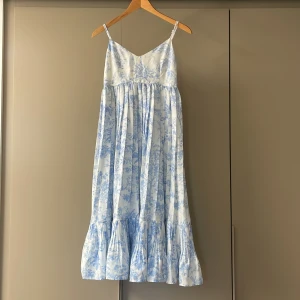 Blåvit sommarklänning med mönster från H&M - Säljer en luftig blåvit klänning från H&M i storlek 36. Klänningen har smala axelband, v-ringning och ett jättefint vitt och blått mönster. Den är lätt plisserad nedtill och har en avslappnad passform, perfekt för sommaren och varma dagar. Pris kan diskuteras vid snabb affär! 🌸