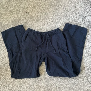 Mörkblå linnebyxor från Gina Tricot - Mörkblå linnebyxor från Gina Tricot med resår i midjan och dragsko. Byxorna har raka ben och är tillverkade i mjukt bomullsmaterial, perfekta för sommaren. För korta för mig som är 160,5. Inte använda någon gång! Stretchiga i midjan. Kom privat om du har någon fråga.