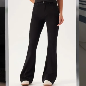 Svarta bootcut jeans - Snygga svarta bootcut jeans med klassisk femficksdesign och hög midja. Jeansen har utsvängda ben och stängs med knapp och dragkedja. Perfekta till sneakers eller boots för en cool look.