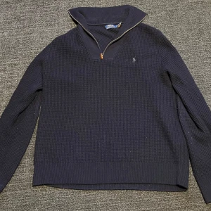 Mörkblå stickad tröja med dragkedja från Polo Ralph Lauren - Säljer en mörkblå stickad tröja från Polo Ralph Lauren med halv dragkedja och hög krage. 