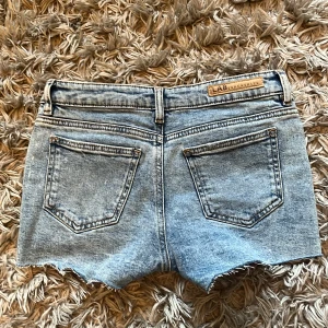 Ljusblå jeansshorts - Säljer ett par ljusblå jeansshorts från LAB Industries med råa, fransiga benslut och klassisk femficksdesign. Shortsen har normal passform och bälteshällor i midjan. Perfekta för varma dagar!