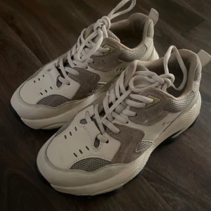 Chunky sneakers från NA-KD i beige och vitt - Säljer ett par chunky sneakers från NA-KD i beige och vitt med grå meshdetaljer. Skorna har kraftig sula, snörning och rund tå. Perfekta för en trendig och sportig look. De är använda två gånger så de är i  nytt skick samt ingen doft/svettlukt🌸💞