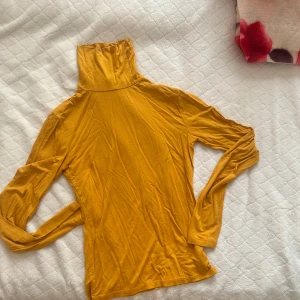 Senapsgul polotröja från NA-KD – storlek XS - Tight och stretchig polotröja från NA-KD i varm senapsgul färg. Använd endast en gång – i nyskick. Perfekt för lager-på-lager eller till vardags. Storlek XS. 