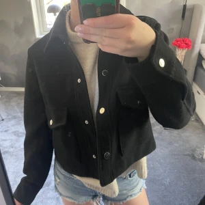 Svart croppad jacka från Zara - Säljer en svart croppad jacka från Zara med klassisk krage. Passar snyggt till både jeans och kjol. Den är lite nopprig, annars bra skick!