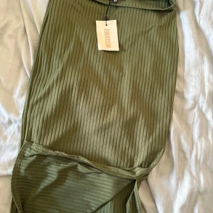 Olivgrön ribbad kjol från Missguided - Säljer en olivgrön ribbad kjol från Missguided. Kjolen är lång och har en tight passform med stretchigt material. Perfekt för dig som gillar stilrena plagg med lite edge.