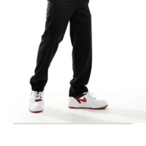 Svarta byxor från ASOS DESIGN - Svarta byxor från ASOS DESIGN med elastisk midja och rak passform. Byxorna har en enkel och stilren look, perfekta för en avslappnad stil. Midjemått W32/L32.