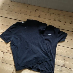 2 st Nike T-shirts  - Säljer två svarta Nike T-shirts, båda i bra begagnat skick utan fläckar eller hål – endast normalt slitage. Den ena är i storlek XS men sitter som en S, med en stilren och minimalistisk broderad Nike Swoosh på bröstet. Den andra är i storlek M, men sitter också som en S, med en klassisk Nike-logga med både text och Swoosh på vänstra bröstet. Båda tröjorna är mjuka, bekväma och av hög kvalitet, perfekta till både vardags och träning. Passar dig som gillar enkel, sportig stil med en