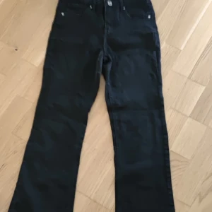 Svarta bootcut jeans - Svarta jeans med bootcut passform och klassisk femficksdesign. Byxorna har knapp och dragkedja framtill samt raka ben som blir vidare nedtill. Perfekta för en stilren look.