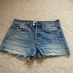 Blå jeansshorts från ZARA - Klassiska blå jeansshorts från ZARA med råa, fransiga benslut och femficksmodell. Shortsen har normal passform och stängs med knapp och dragkedja. Perfekta för varma dagar och enkel stil.