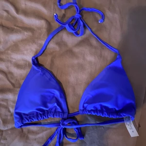 Blå trekantsbikini med knyt - Säljer en blå trekantsbikini från SHEIN med knyt i nacken och ryggen. Klassisk modell med justerbara band för perfekt passform. Endast solat med en gång!